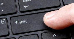 computer shift key with finger pressing button on white background