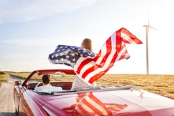 Woman holding an American flag on a road trip                                