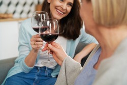 Close up of mother and adult daughter toasting in wine