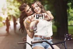Hippie girls taking selfie at park 