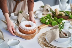 Hands of unrecognizable woman setting table with an easter cake