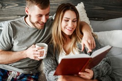 Young couple reading book at bedroom 