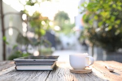 White coffee cup with tablet and notebook at outdoor