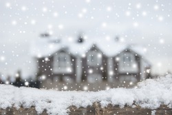 Living place in winter, snowfall. December. Defocused country house with car and fence in snow. Wooden plank in snow in front side.