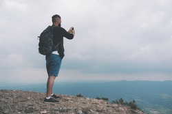 Young hiker taking picture with phone camera of landscape