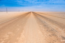 Driving across the Namib Desert in Western Namibia. Endless straight sand, gravel and salt roads