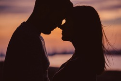 Silhouette of young couple having romantic moments against the sunset background. Silhouette of romantic couple stand huggins