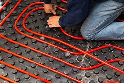 Worker who install tubes of radiant underfloor heating installation 