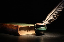 Vintage still life with old book and quill pen on dark background