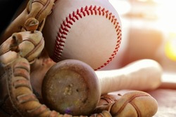 A close up image of an old used baseball, baseball bat, and baseball glove. Old Vintage with  glove baseball on black background. 