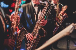Concert view of a saxophonist, saxophone sax player with vocalist and musical during jazz orchestra performing music on stage 