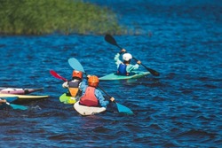 Kids learn kayaking, canoeing whitewater training in the lake river, children practicing paddling, yound kayakers in a summer camp
