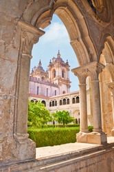 Awesome arch window view of the main church in the Alcobaca Monastery complex in Portugal. The Gothic cathedral is surrounded by inner courtyard. The building is part of UNESCO World Heritage. 