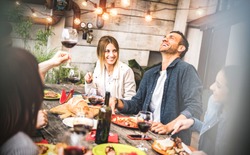 Young friends having fun drinking red wine on balcony at house dinner pic nic party - Hipster millennial people eating bbq food at fancy restaurant together - Dinning life style concept on warm filter