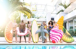 Front view of friends at swimming pool party with lilo airbed and swim wear - Youth vacation concept with happy guys and girls having fun in summer day at luxury resort - Warm bright saturated filter