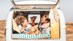 Hipster couple with cute dog traveling together on vintage minivan - Wanderlust and life inspiration concept with hippie family on mini van adventure trip - Bright warm filter