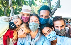 Multiracial milenial friends taking selfie with closed face masks during Covid second wave outbreak - New normal lifestyle concept with young people having fun together - Bright vivid backlight filter