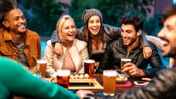 Happy friends drinking beer at brewery bar dehor - Friendship lifestyle concept with young milenial people enjoying time together at open air pub - Warm color tones on vivid filter with focus on girls