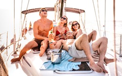 Happy young friends having fun at sailboat party - Wanderlust travel concept with millenial people on sailing trip - Luxury lifestyle on exclusive summer mood - Warm sunshine halo filter