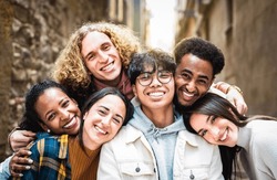 Multi racial guys and girls taking selfie outdoors with backlight - Happy life style friendship concept on young multiracial best friends having fun day together in Barcelona city - Warm vivid filter