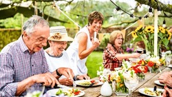 Happy senior people group having fun at pic nic barbecue garden diner - Food life style concept with mature friends cooking out at barbeque grill fest - Warm vivid filter with focus on left woman