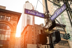 Street sign of Fifth Ave and West 33rd St at sunset in New York City - Urban road concept direction in Ny Manhattan downtown - American world famous capital destination on warm dramatic filtered look