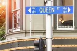 Street sign of Queen Street in Auckland - Urban concept and road direction in the biggest city of New Zealand - Australasian world famous destination with warm filter and enhanced sunshine halo