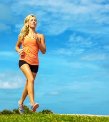 Full length of attractive young female athlete jogging on sidewalk at beach
