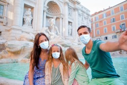 Family wearing face masks at Fontana di Trevi, Rome, Italy. Coronavirus flu virus travel concept banner.