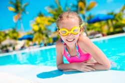 Cute little beautiful girl swims in outdoor swimming pool
