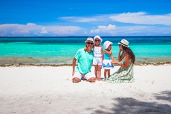 Happy beautiful family with kids walking together on tropical beach during summer vacation