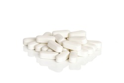 A pile of calcium vitamin supplement tablets isolated on a white background.