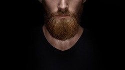 Perfect beard. Close-up of young bearded man standing against black background