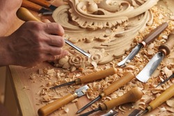 Wood carving. Carpenter's hands use chiesel. Senior wood carving professional during work. Man working with woodcarving instruments