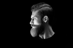 Man portrait. Black and white dramatic light portrait of confident young bearded man looks into the distance. Stylish young man red beard. Light accent on the beard and hair