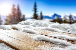Snow on a wooden table in alpine mountain surroundings on a beautiful winter day
