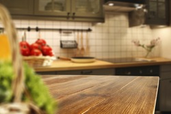Wooden table of free space in kitchen and blurred vegetables 