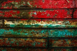 Colorful planks of the damaged hull of the cutter. Vintage rusty old boat background. Vestamanna, Faroe Islands. Denmark.