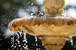Close-up of an old stone fountain with dripping water and blurred background