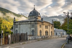 Old Jewish synagogue in Oni village, Racha region, Georgia. Historic synagogue building with snowy peaks of Caucasus Mountains at background.