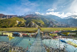 Suspension bridge with buddhist prayer flags on the Annapurna circuit trek in Nepal. Shangri-la land