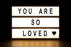 You are so loved light box sign board on wooden table. 