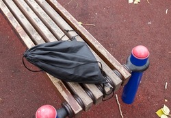 A lost school backpack lying on a park bench. A lonely bag in the park.