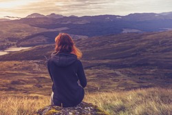 Woman sitting on mountain top and contemplating the sunset