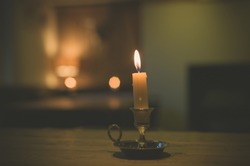 A lit candle on a table in a dining room