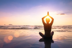 Yoga and meditation on the calm peaceful beach at sunset, fit young woman
