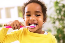 Little beautiful african girl brushing teeth, healthy concept
