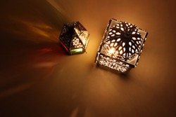 Couple of glowing Moroccan ornamental lanterns on table. Decorative golden shadows. Greeting card, invitation for Muslim holy month Ramadan Kareem. Festive background. Flat lay, top view.