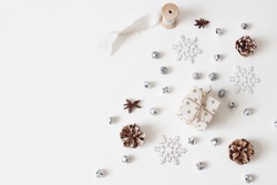 Christmas styled stock composition. Glittering silver jingle bells, snowflakes, pine cones, silk ribbon and anise stars isolated on white table background.Flat lay, top view. Winter decorative pattern