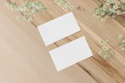 Set of two blank business cards and cow parsley flowers. Old wooden table. Flat lay, top view, selective focus, blurred background. Feminine stationery. Wedding, birthday desktop mock-up scene. 